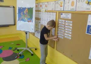 Chłopiec przyczepia na tablicy nazwę kraju należącego do Unii Europejskiej.